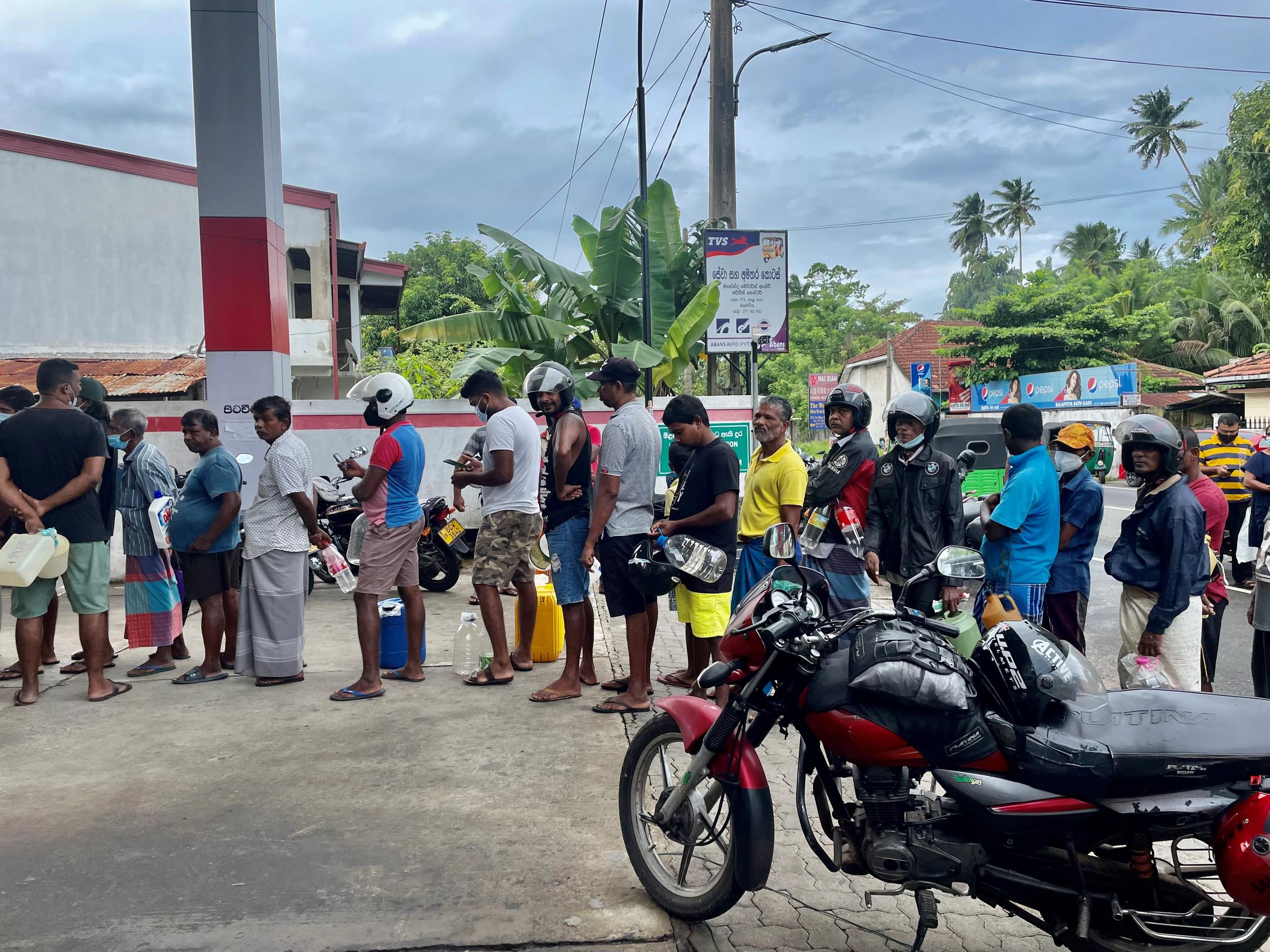 Ľudia čakajúci na benzín s fľaškami v ruke 