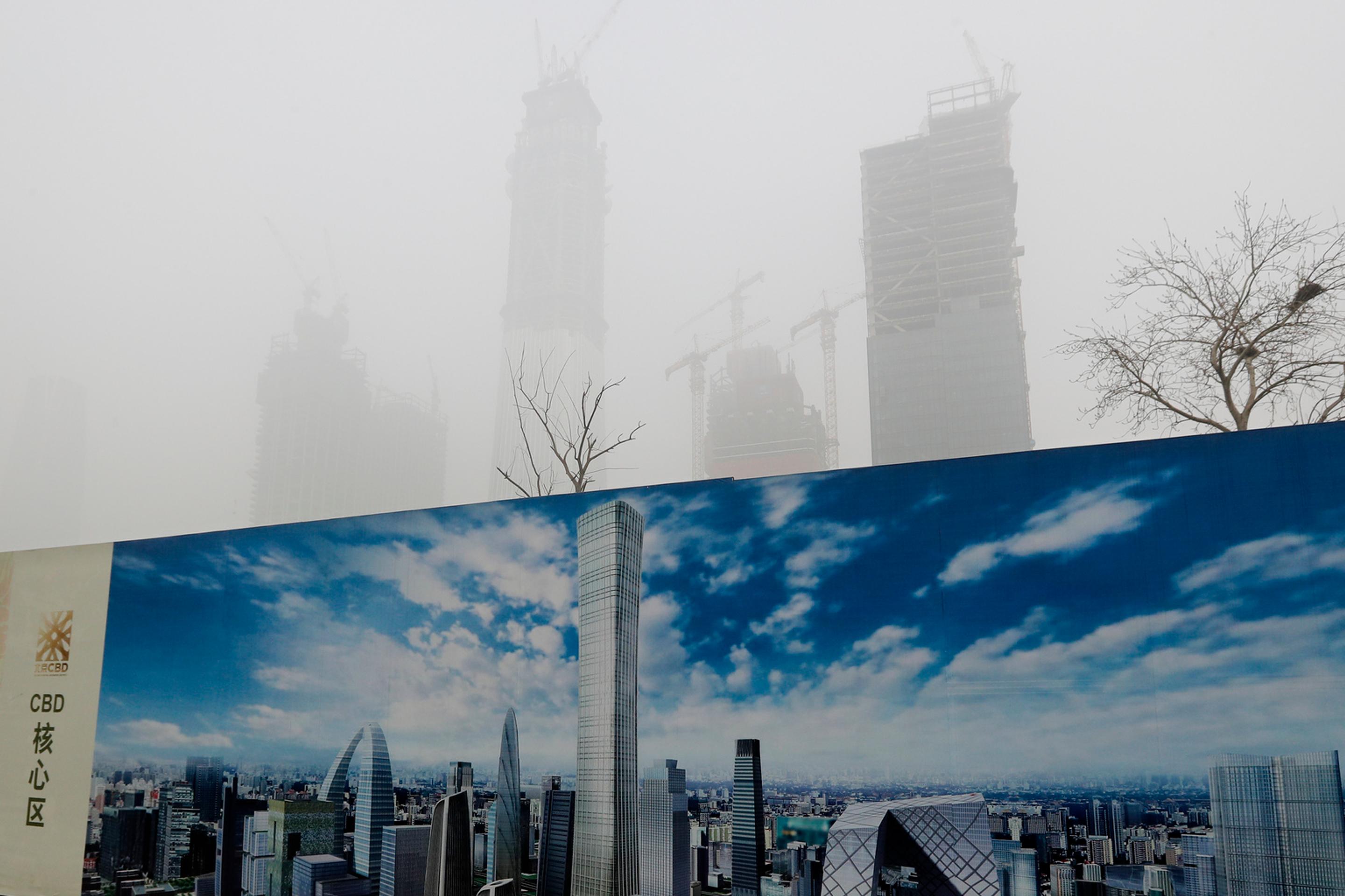 Do smogu zahalená obloha nad Pekingom v kontraste s panorámou na bilborde.