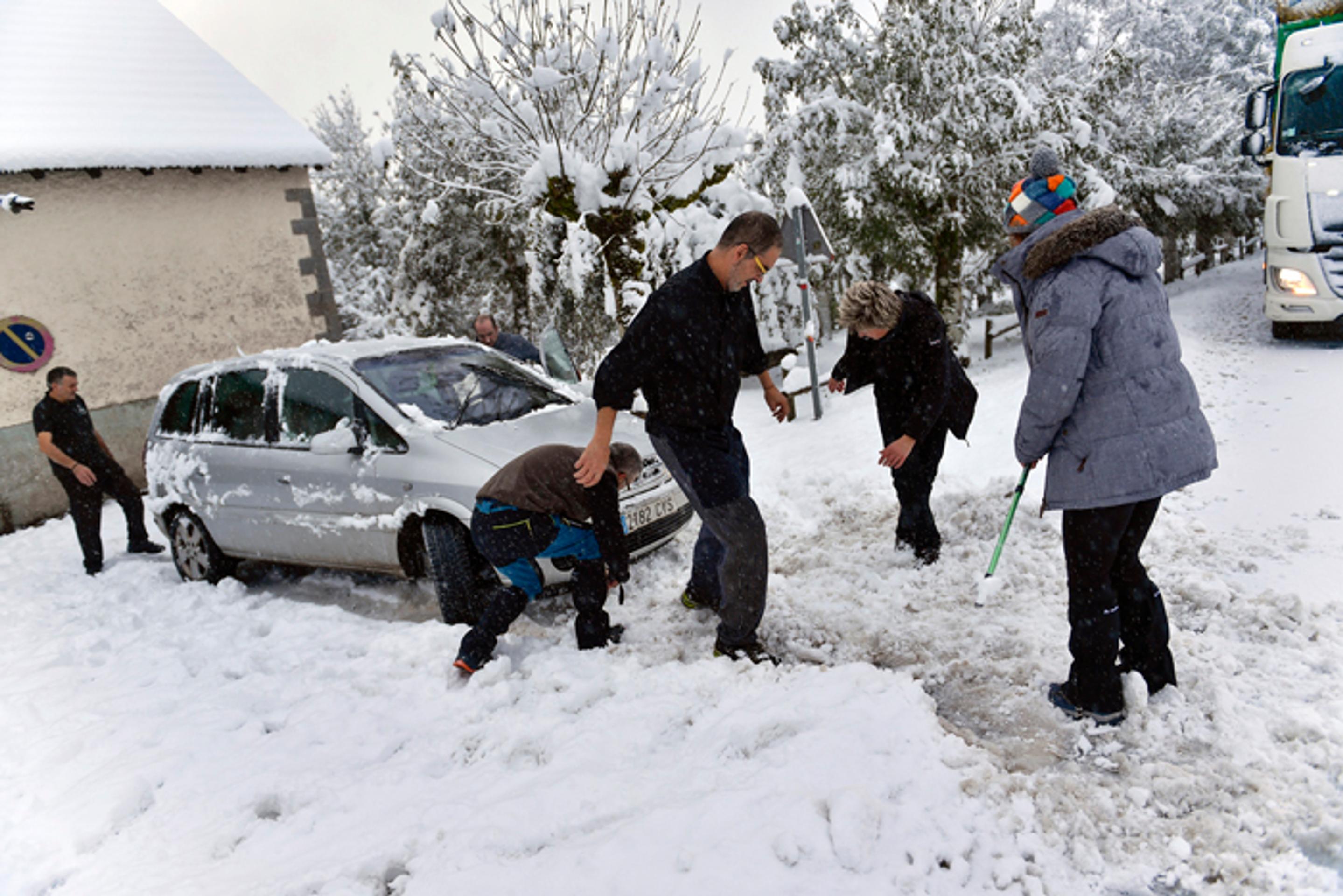 Ľudia pomáhajú odhrabať auto po silnom snežení v severošpanielskom Roncesvallese.