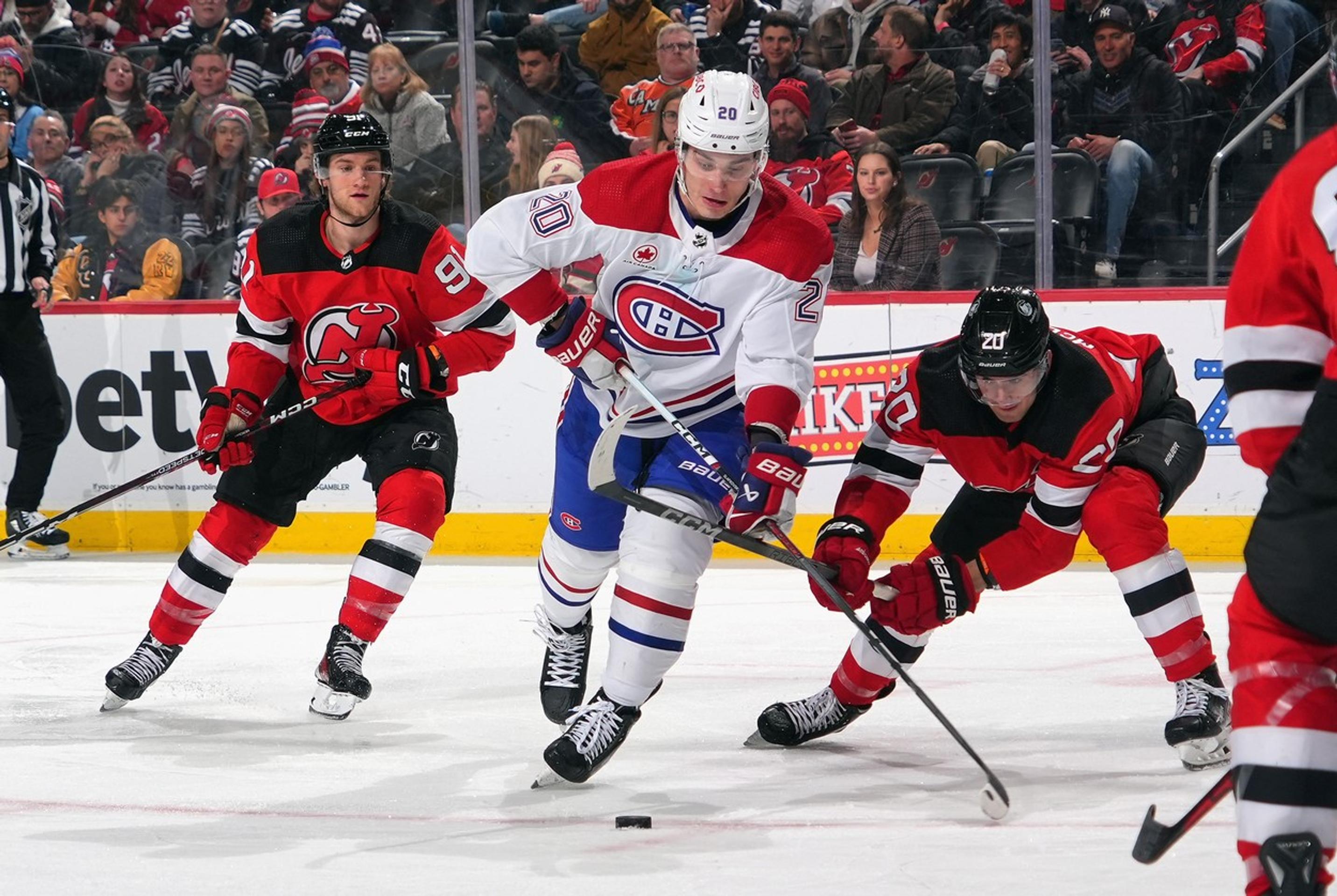 Juraj Slafkovský (v bielom) z Montrealu a Michael McLeod (napravo) z New Jersey v súboji o puk.