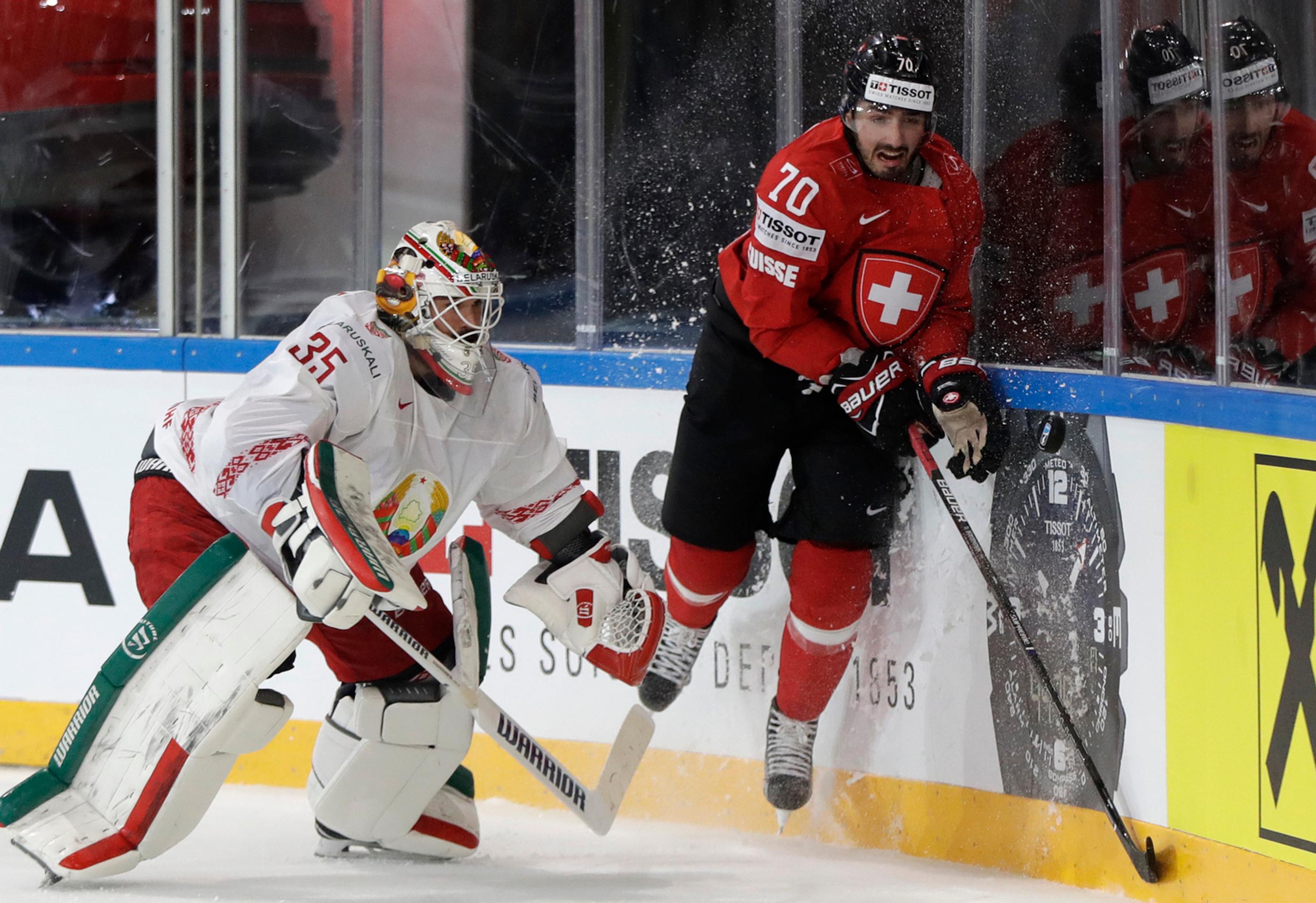 Gólman Bieloruska Kevin Lalande (vľavo) sa snaží chytiť puk pred Denisom Hollensteinom v dueli MS 2017.