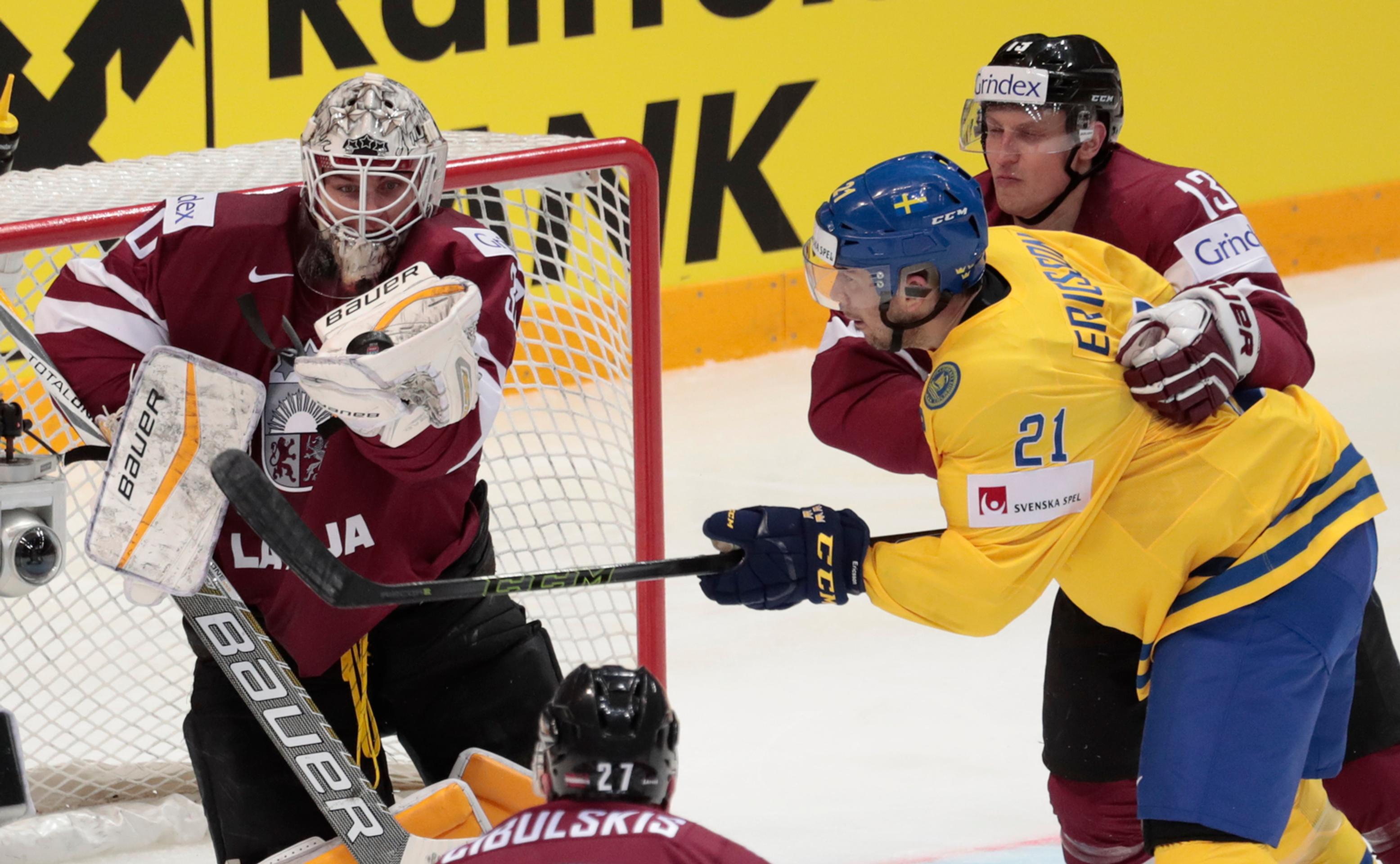 Švéd Jimmie Ericsson v súboji s lotyšským brankárom Elvisom Merzlikinsom a jeho spoluhráčom Guntisom Galvinsom počas duelu MS v 