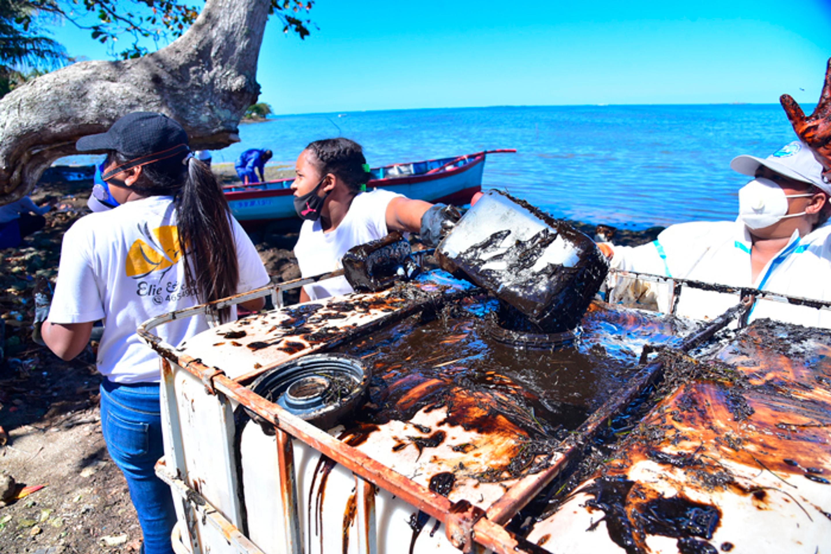 Dobrovoľníci počas odstraňovania ropných látok uniknutých z lode uviaznutej na plytčine pri pobreží ostrova Maurícius.