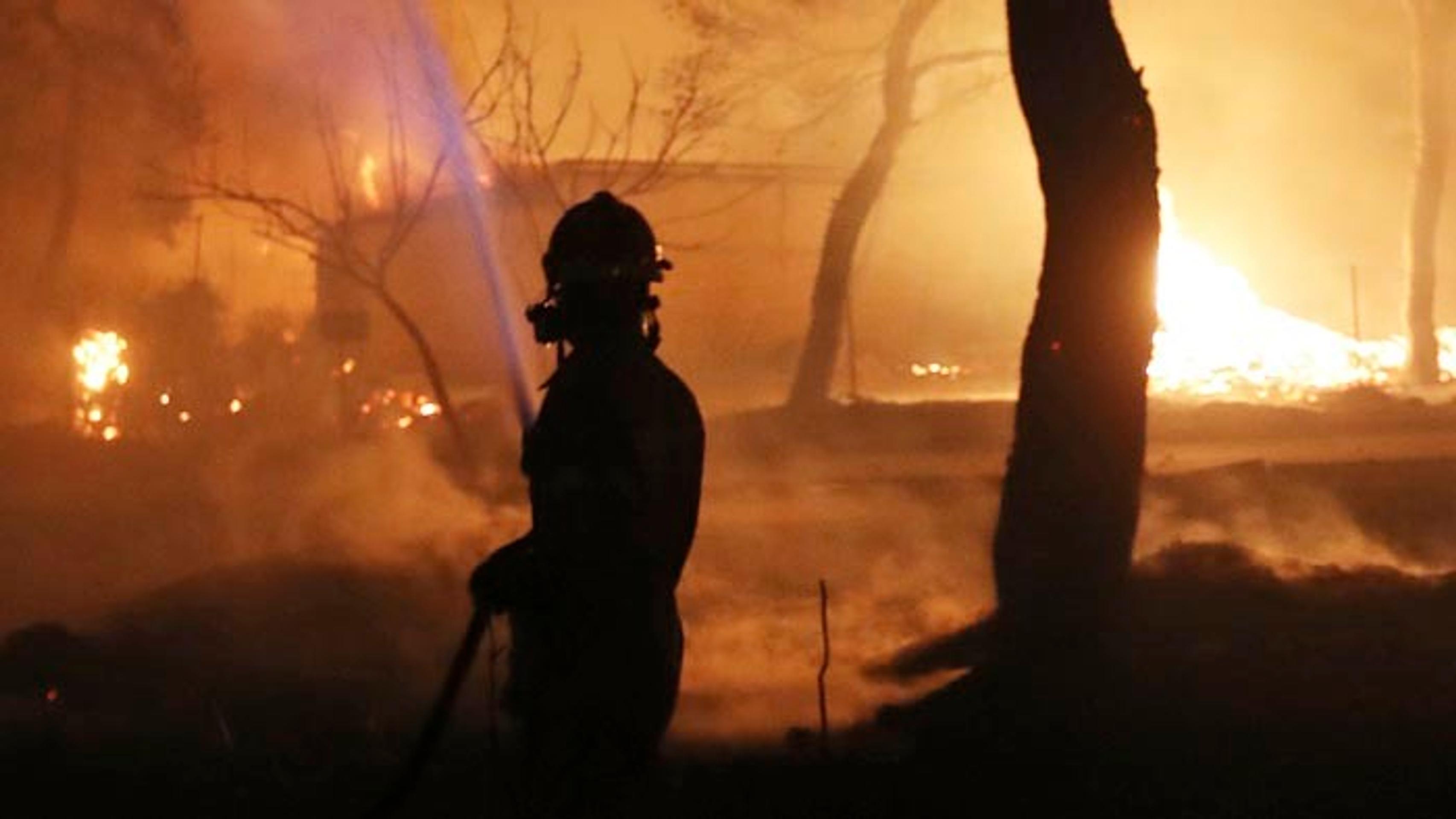 Hasič hasí lesný požiar v gréckom meste Mati.