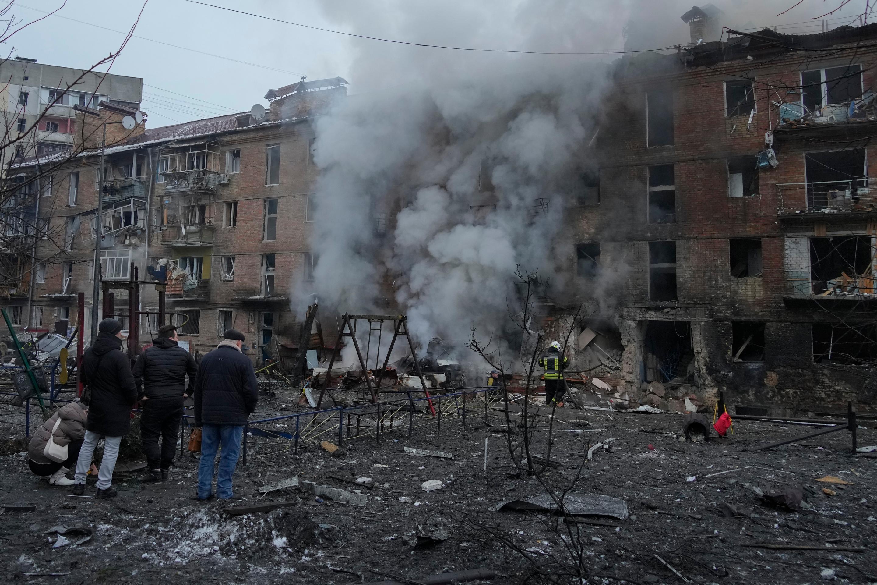 Ľudia si prezerajú materiálne škody na obytnej budove po ruskom raketovom útoku v Kyjeve.