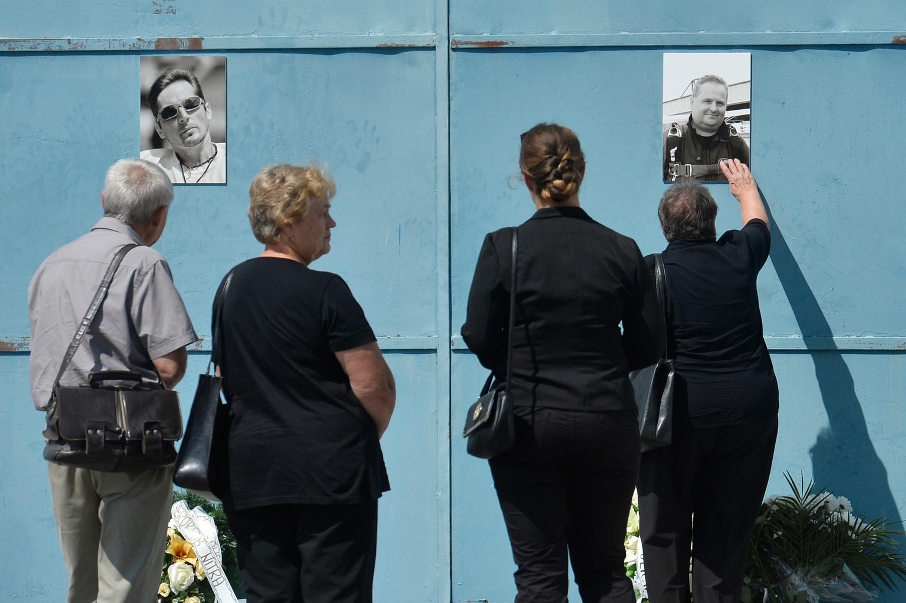 Pozostalí prinášajú kvety k fotografiám obetí leteckého nešťastia na bráne hangára