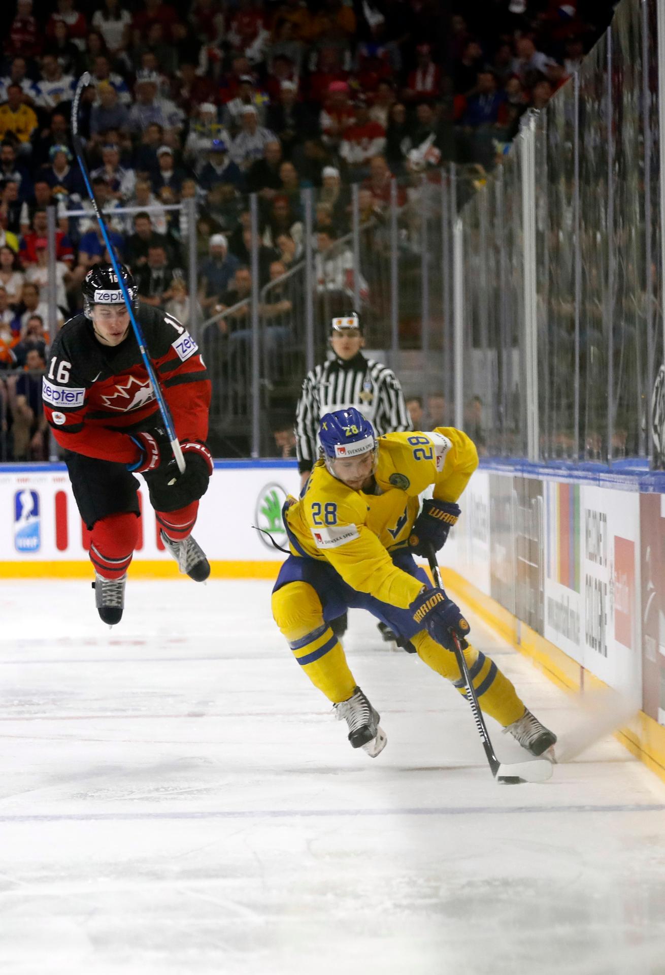 Kanaďan Mitch Marner vo výskoku a Švéd Elias Lindholm s pukom.