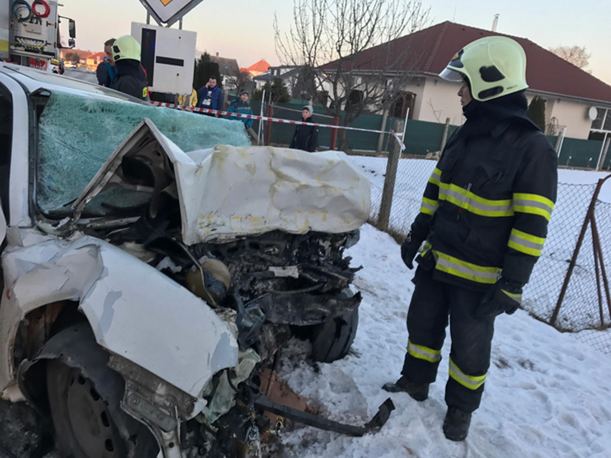 Hasič stojí pri osobnom aute, ktorého predok zdemolovala čelná zrážka s autobusom v Trebaticiach.