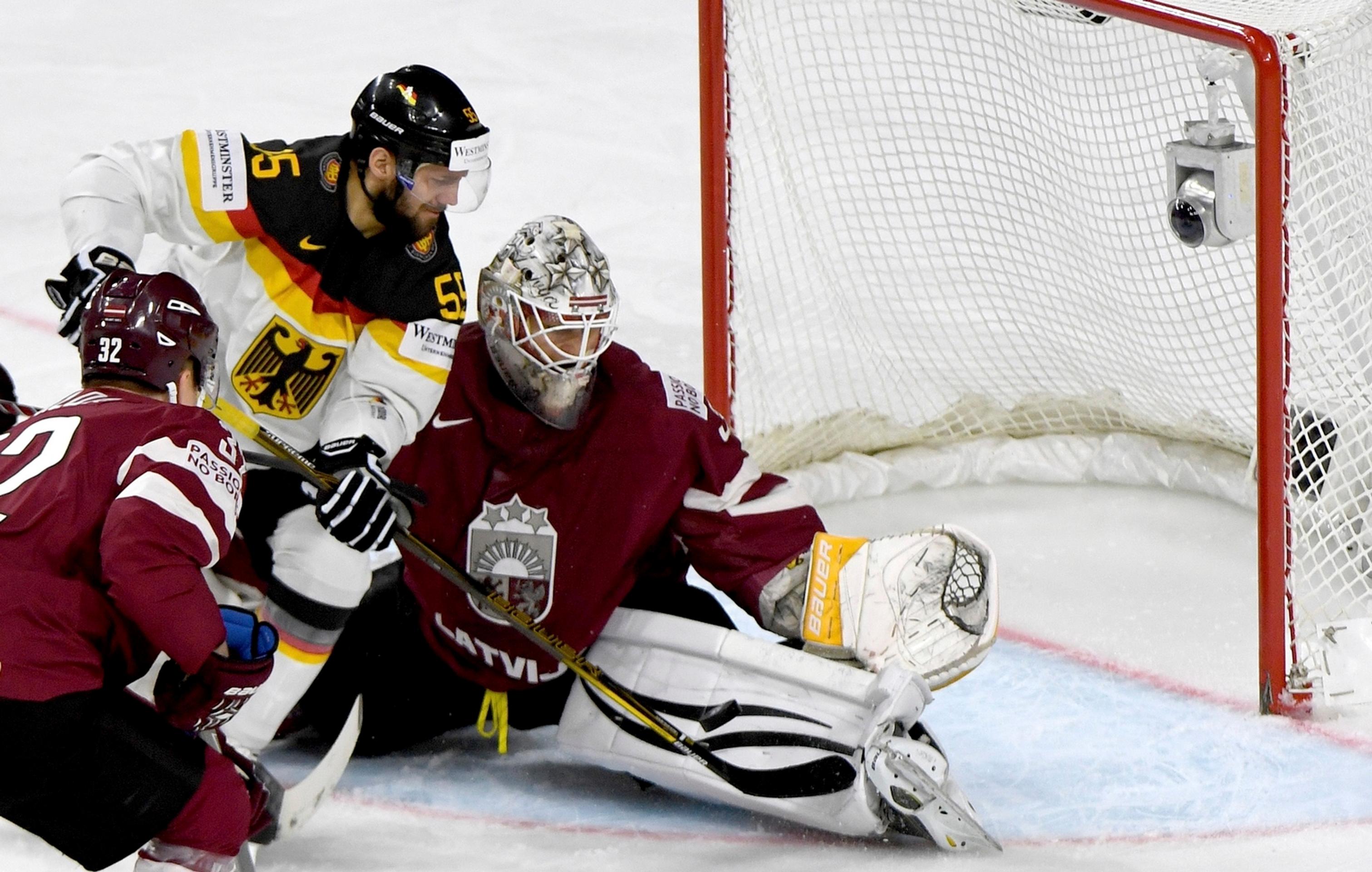 Felix Schütz (vľavo) z Nemecka útočí v dueli MS 2017 na lotyšského gólmana Elvisa Mezlikinša.