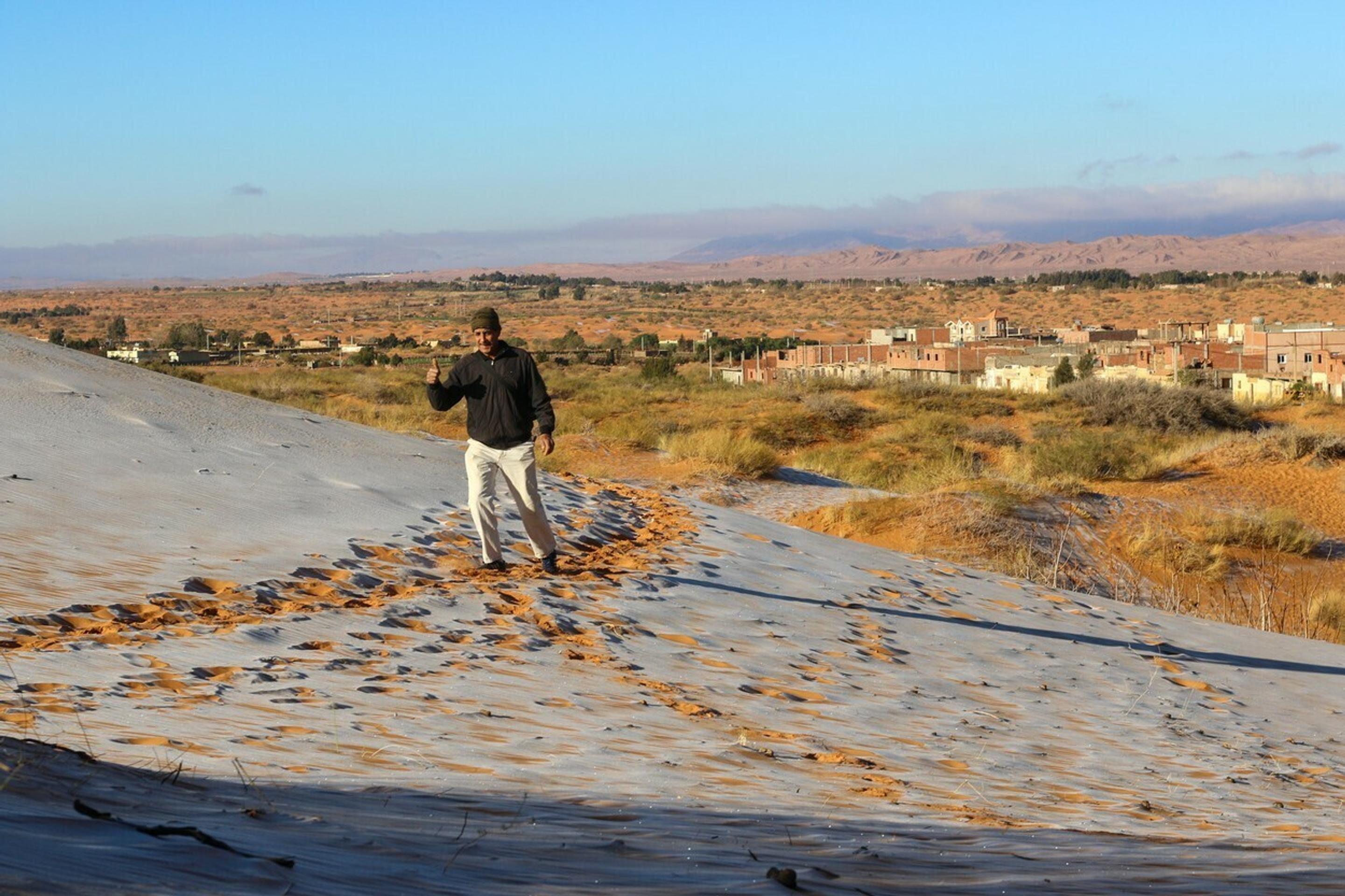 Alžírčan si užíva sneh, ktorý napadol na Sahare.