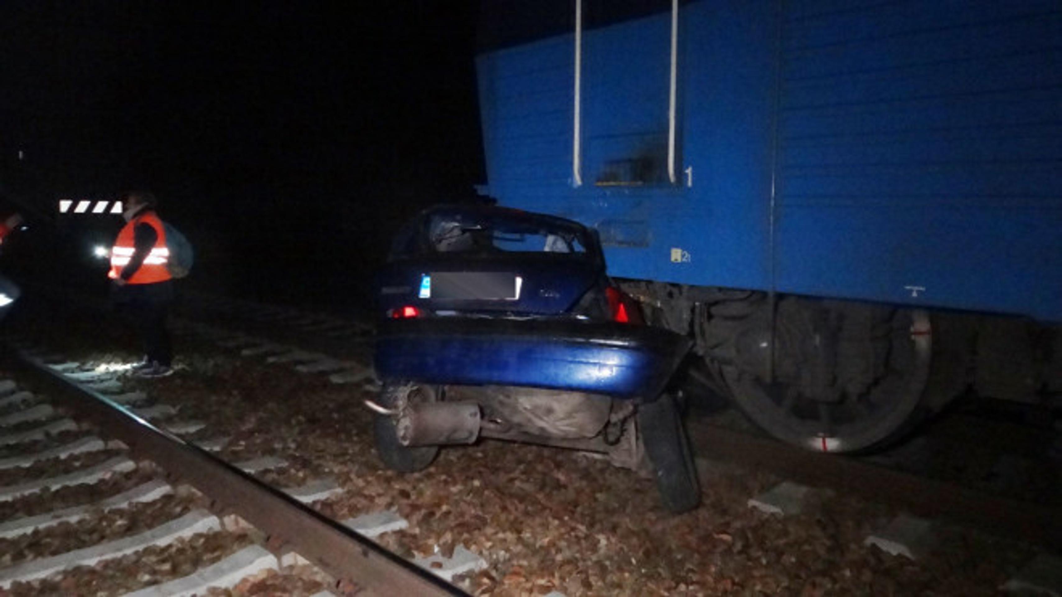 Zošrotované auto vlakom na trati v obci Kařízek na Rokycansku.