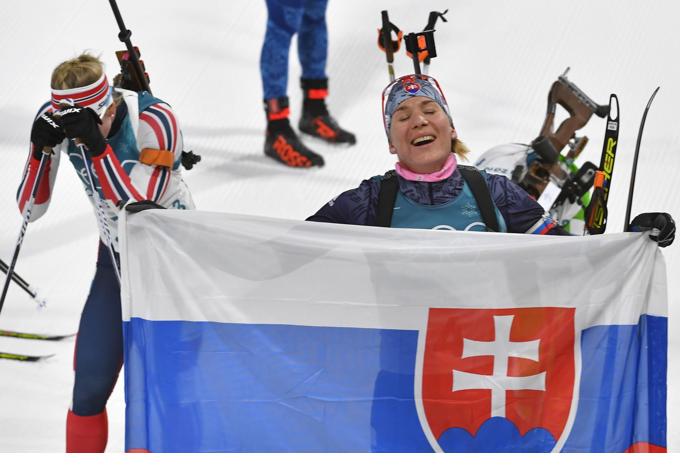 Anastasia Kuzminová drží slovenskú vlajku v cieli po zisku zlatej olympijskej medaily počas pretekov s hromadným štartom.