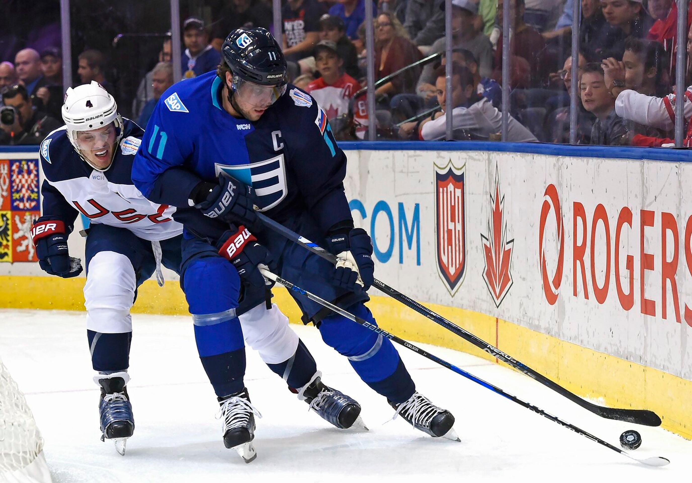 Kapitár Tímu Európy Slovinec Anže Kopitar si kryje puk pred Američanom Johnom Carlsonom.