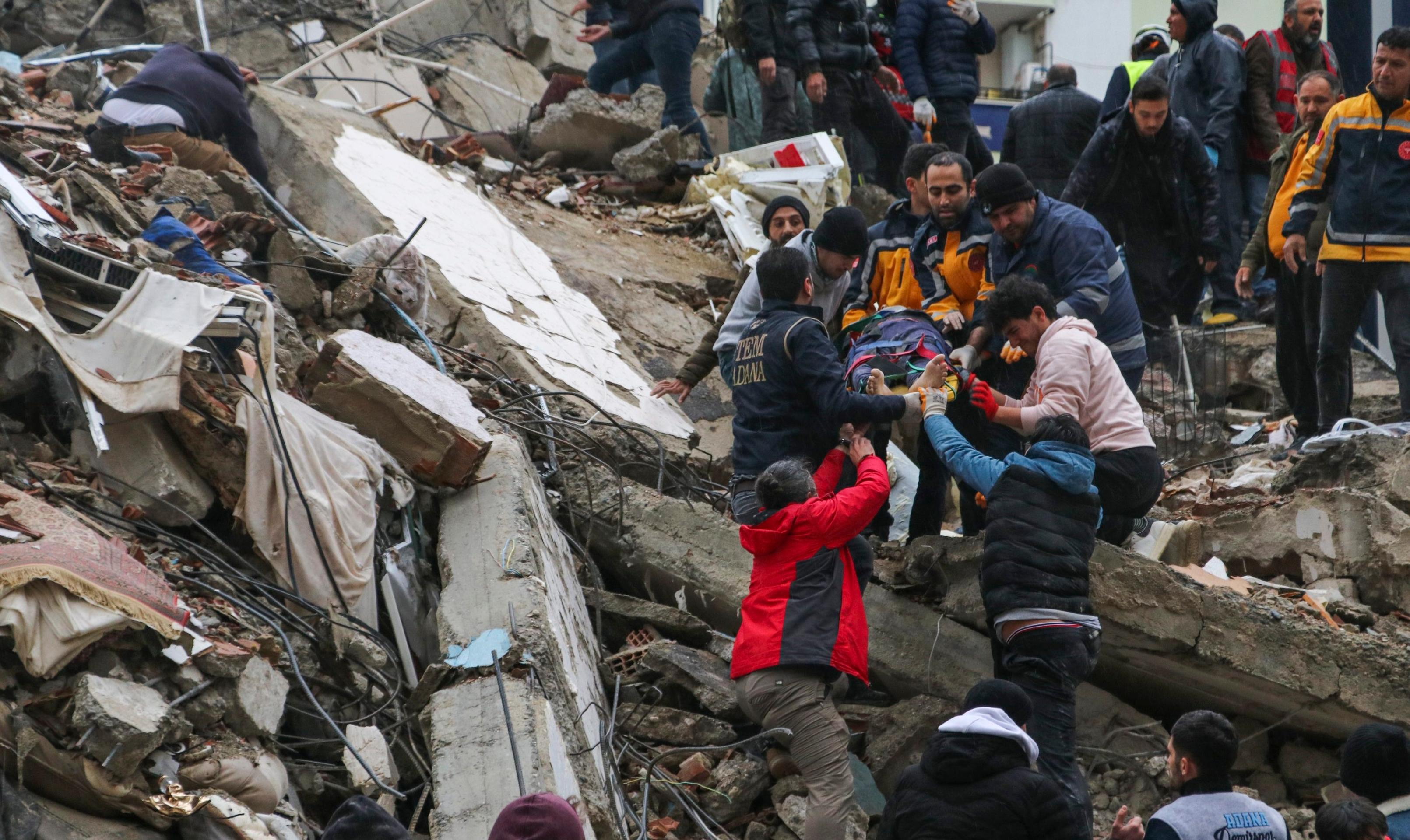 Záchranári v spolupráci s obyvateľmi mesta vynášajú zranených z trosiek budovy v Adane.