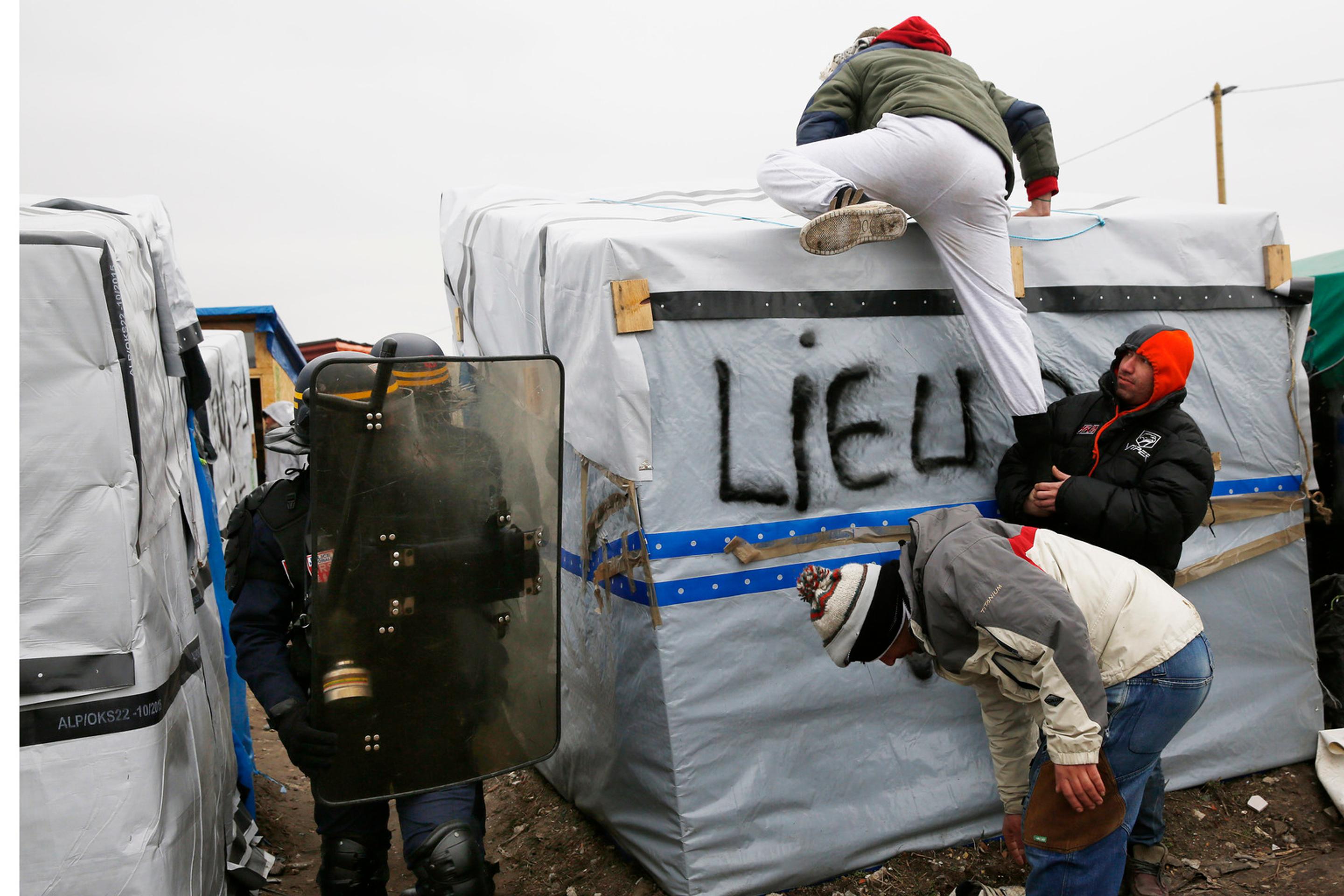 Migranti v tábore pri Calais protestujú na strechách búd.