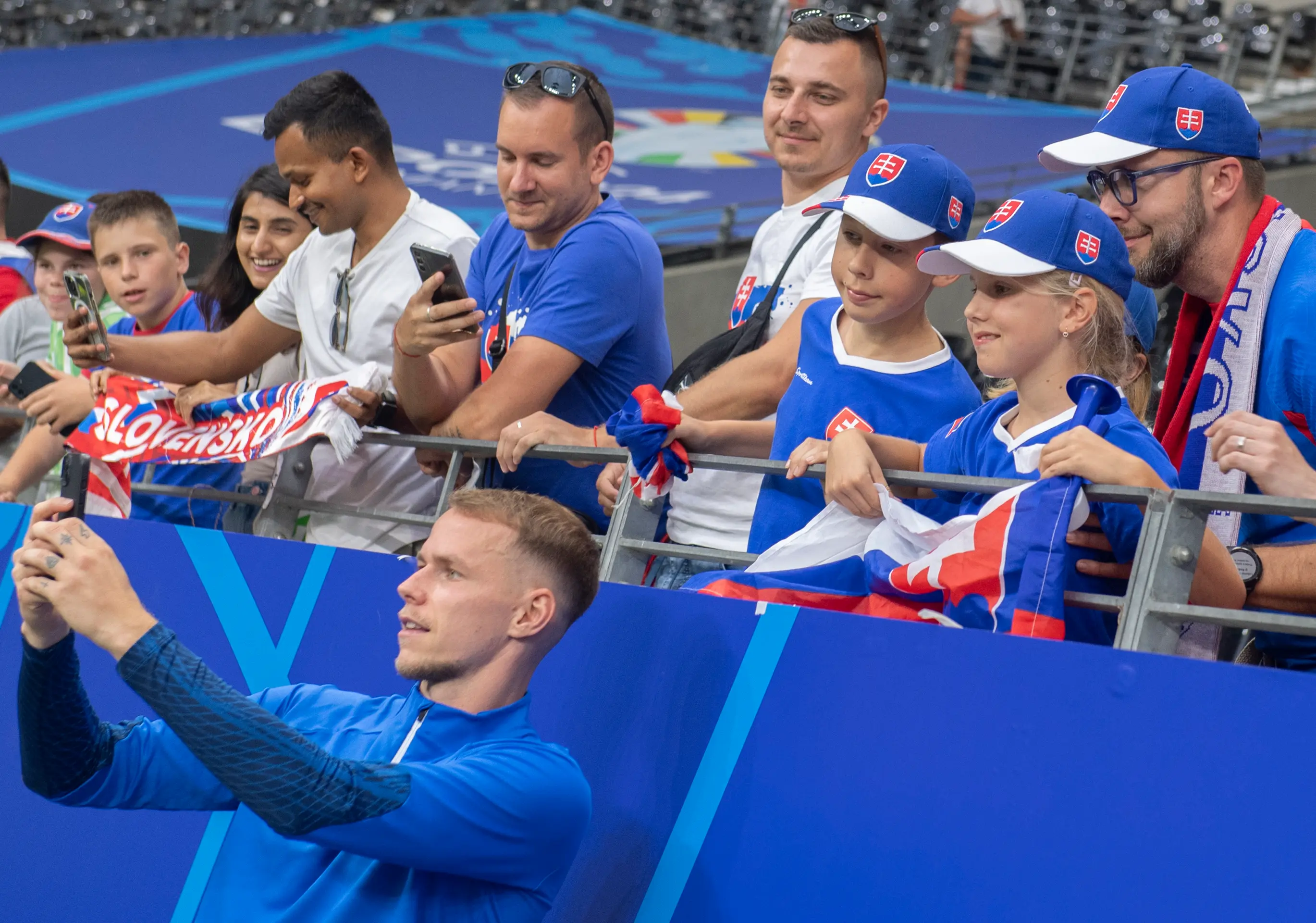 Ondrej Duda (dole) sa fotí s fanúšikmi po zápase s Rumunskom na ME 2024.