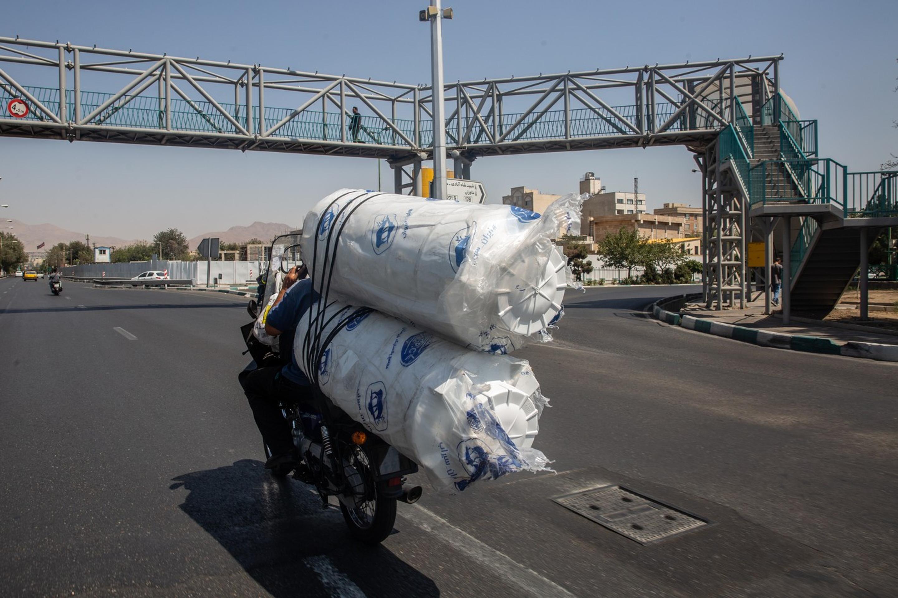 Motocykel prevážajúci vodné nádrže v deň, keď vláda uzavrela hlavné mesto kvôli nedostatku vody a výpadkom elektriny v Teheráne.
