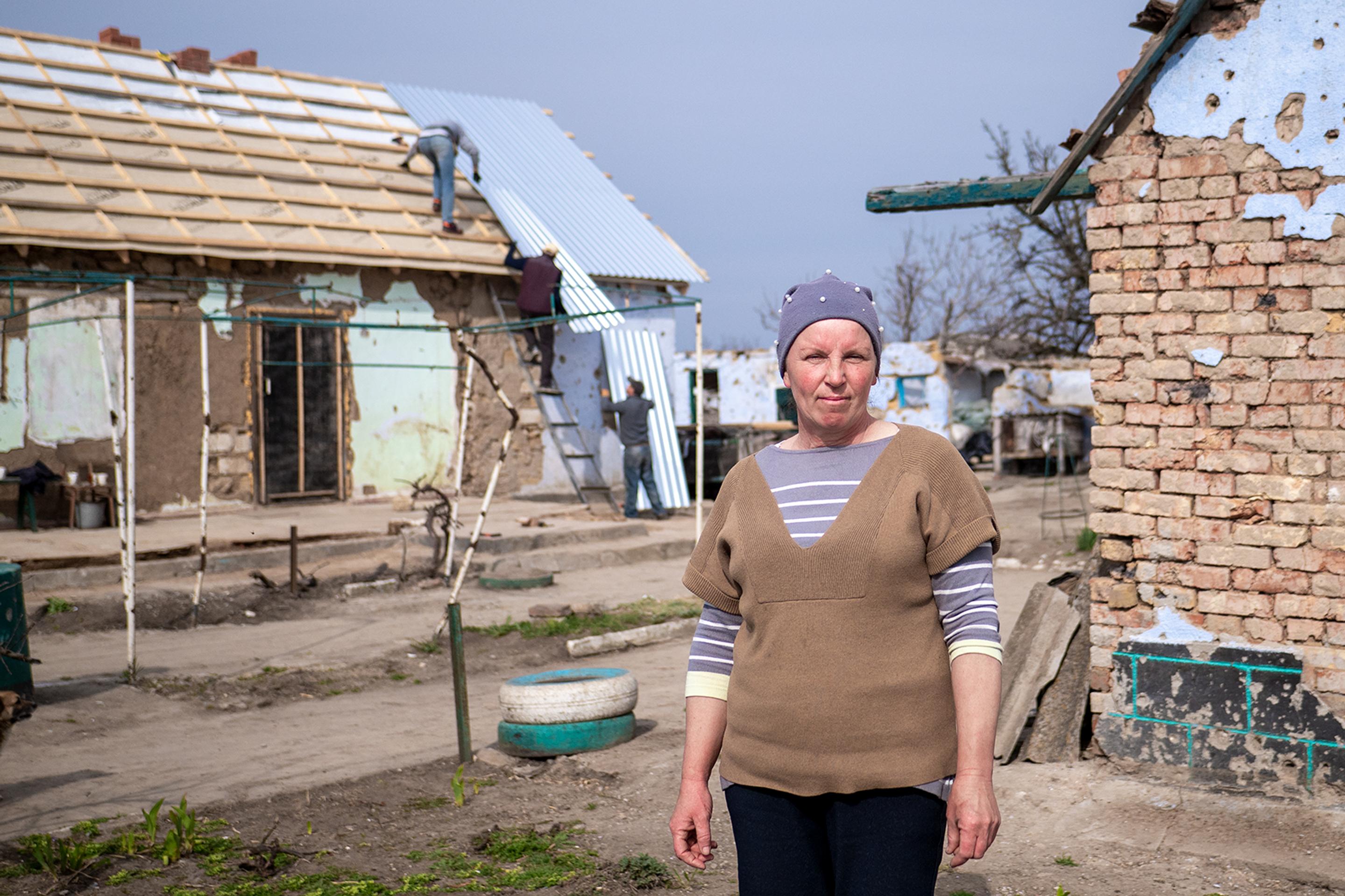 Natália v pozadí s poškodeným domom