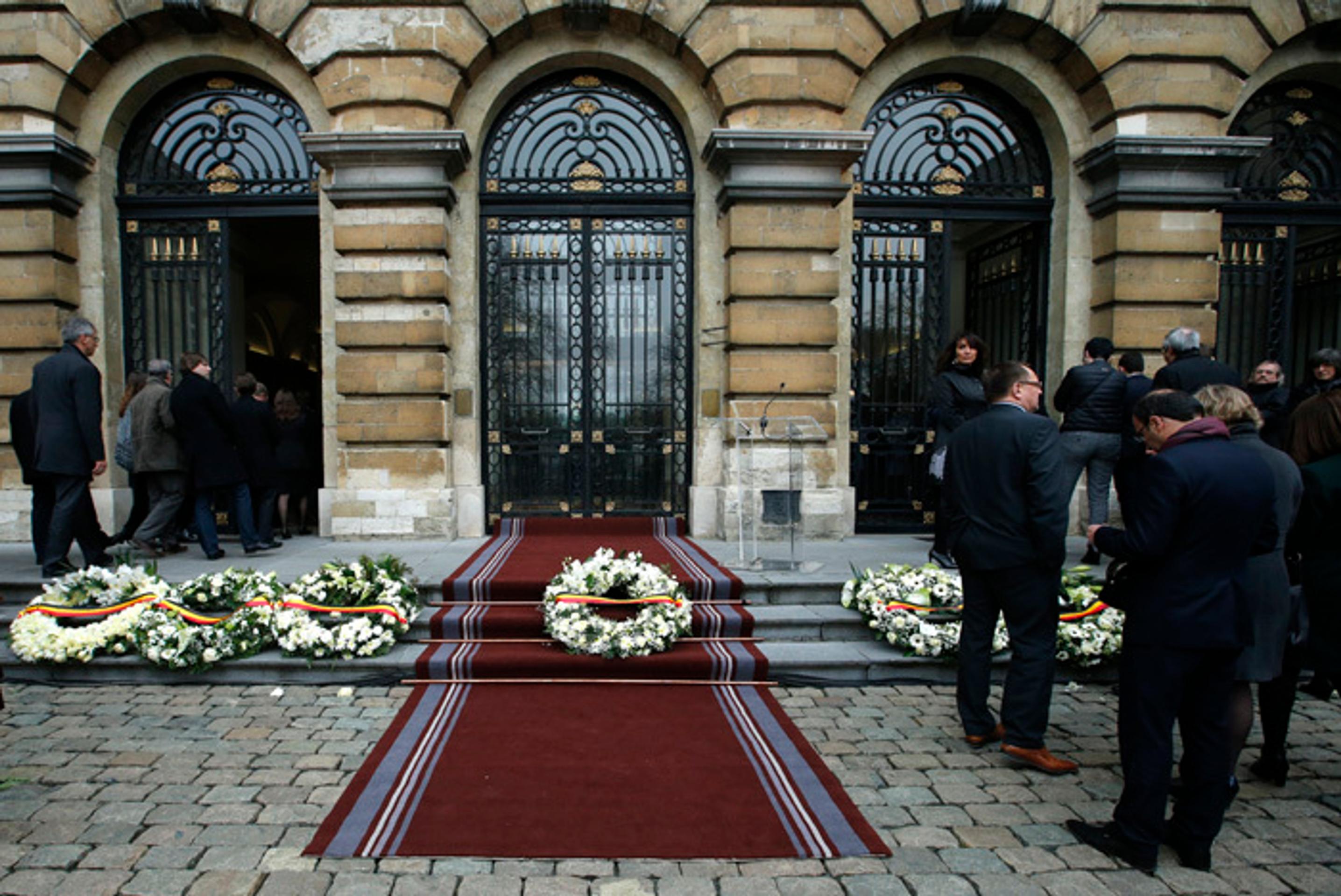 Belgickí poslanci kráčajú okolo vencov položených na pamiatku obetí teroristických útokov pred budovou parlamentu v Bruseli.