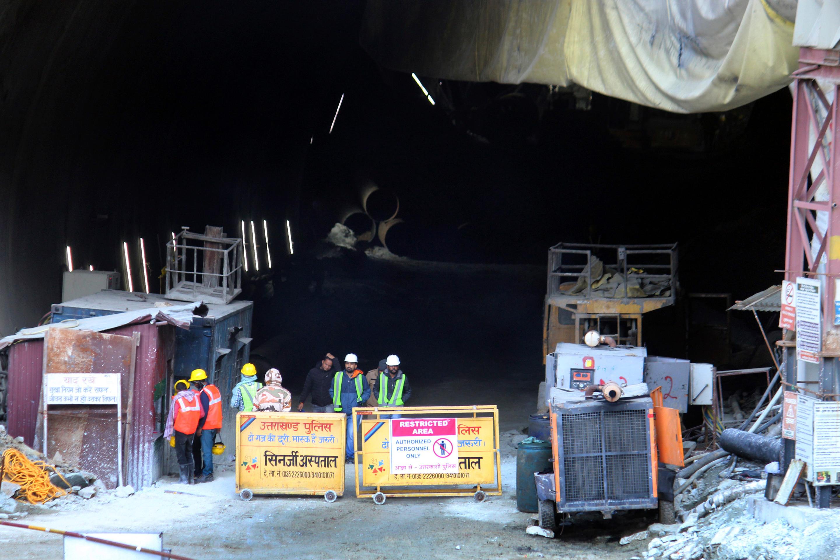 Indickí záchranári stoja pri  zrútenom cestnom tuneli, v ktorom uviazlo asi 40 robotníkov