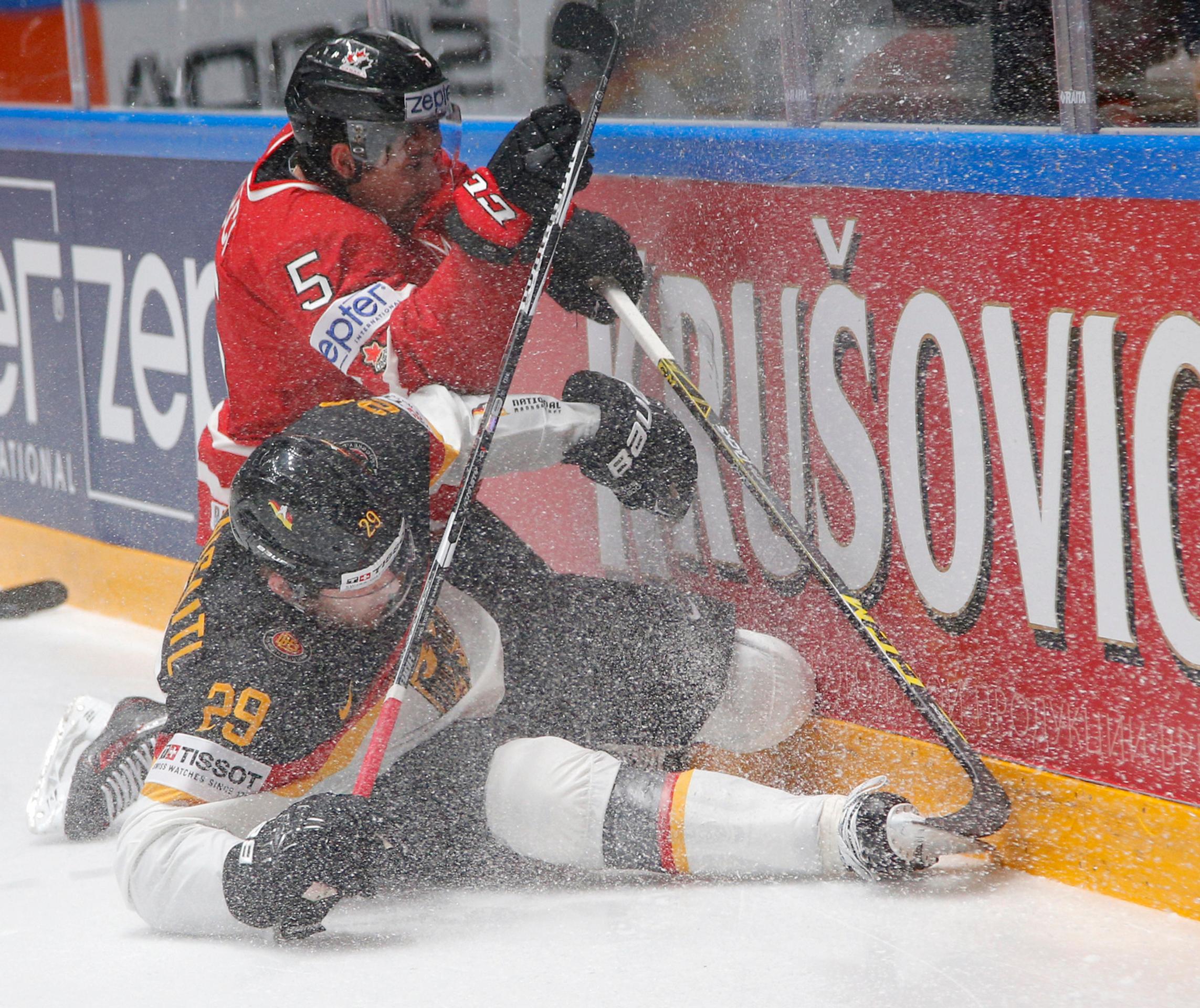 Hráč Kanady Cody Ceci (hore) a hráč Nemecka Leon Draisaitl (dolu) v súboji o puk v zápase B-skupiny MS v Rusku.