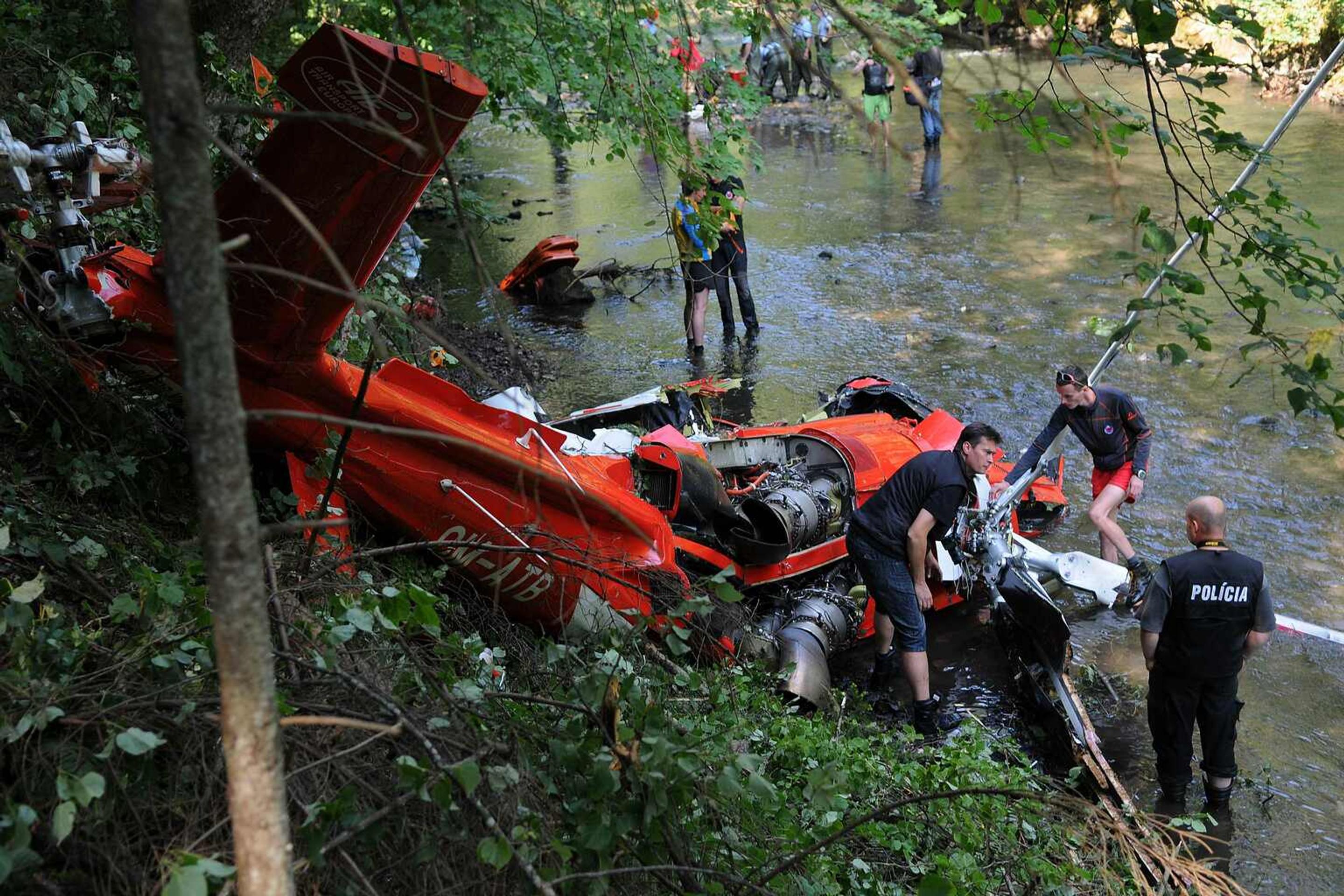 Na snímke polícia, vyšetrovatelia a záchranári skúmajú spadnutý vrak vrtuľníka